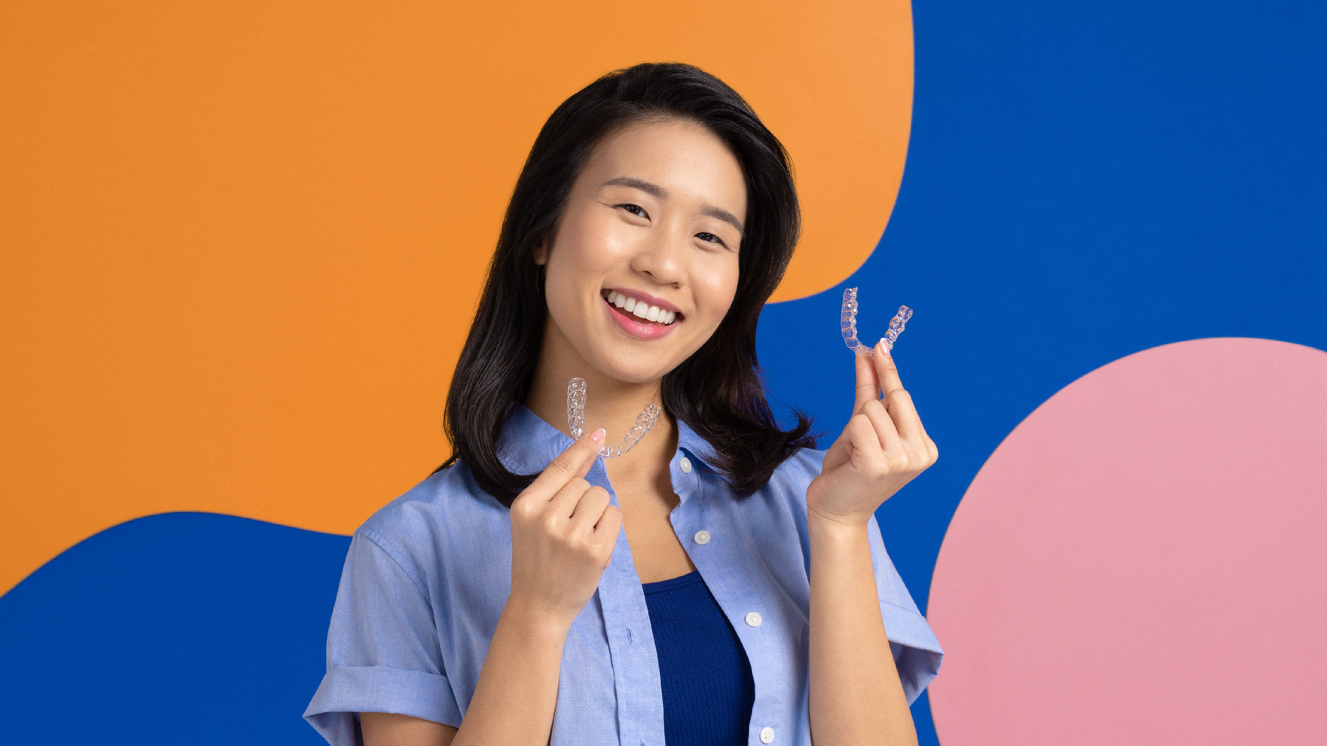Female person holding up clear aligners in both hands