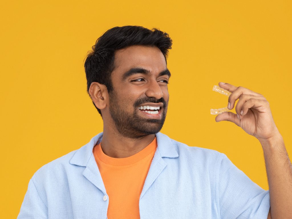Guy smiling and holding clear aligners