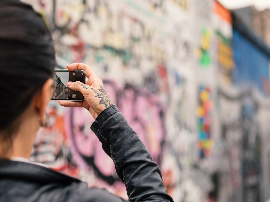 Girl capturing pictures of wall mural
