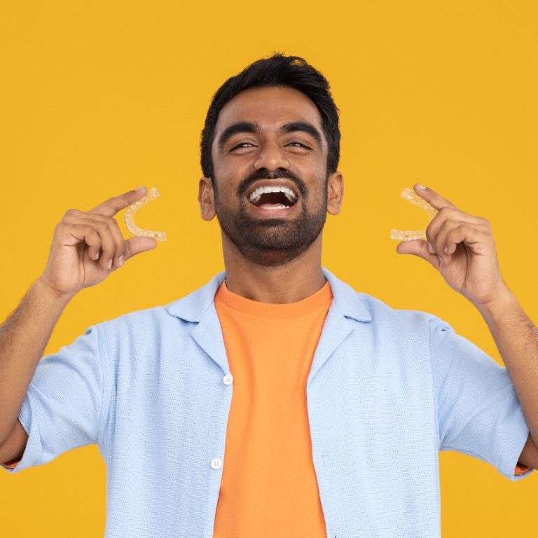 Man holding aligners and smiling widely