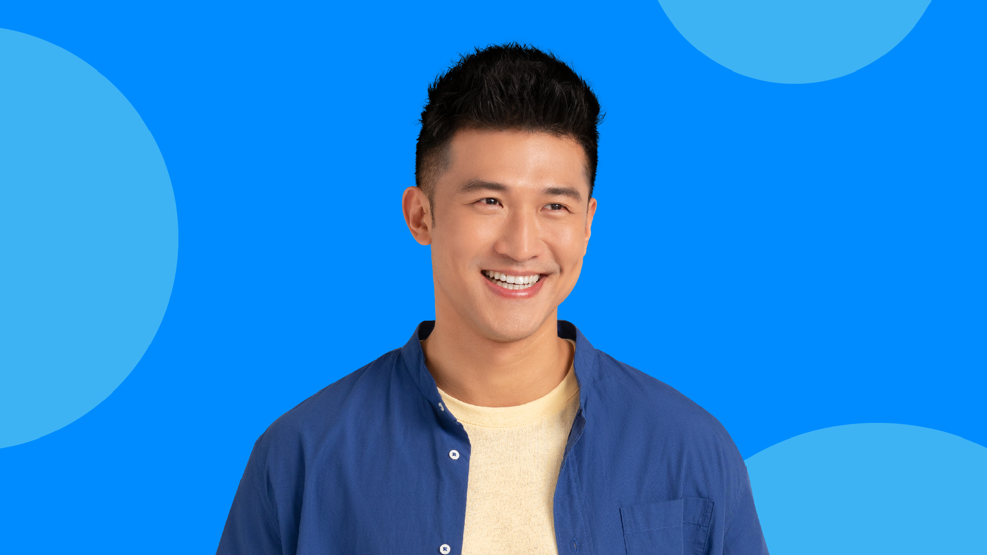 A man smiling wide against a blue background